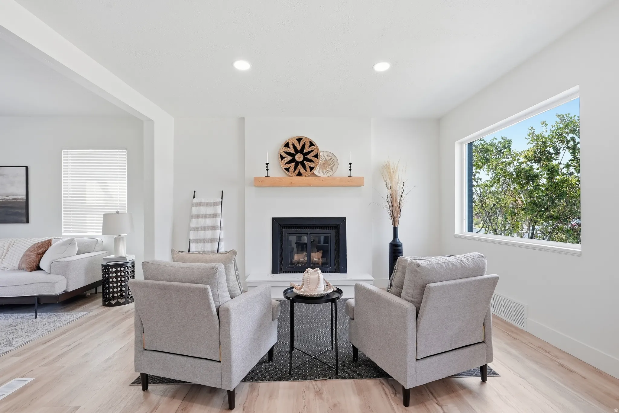 Contemporary living space featuring a built-in fireplace with a hearth, a wood mantel, light wood-finish flooring, and recessed ceiling lighting