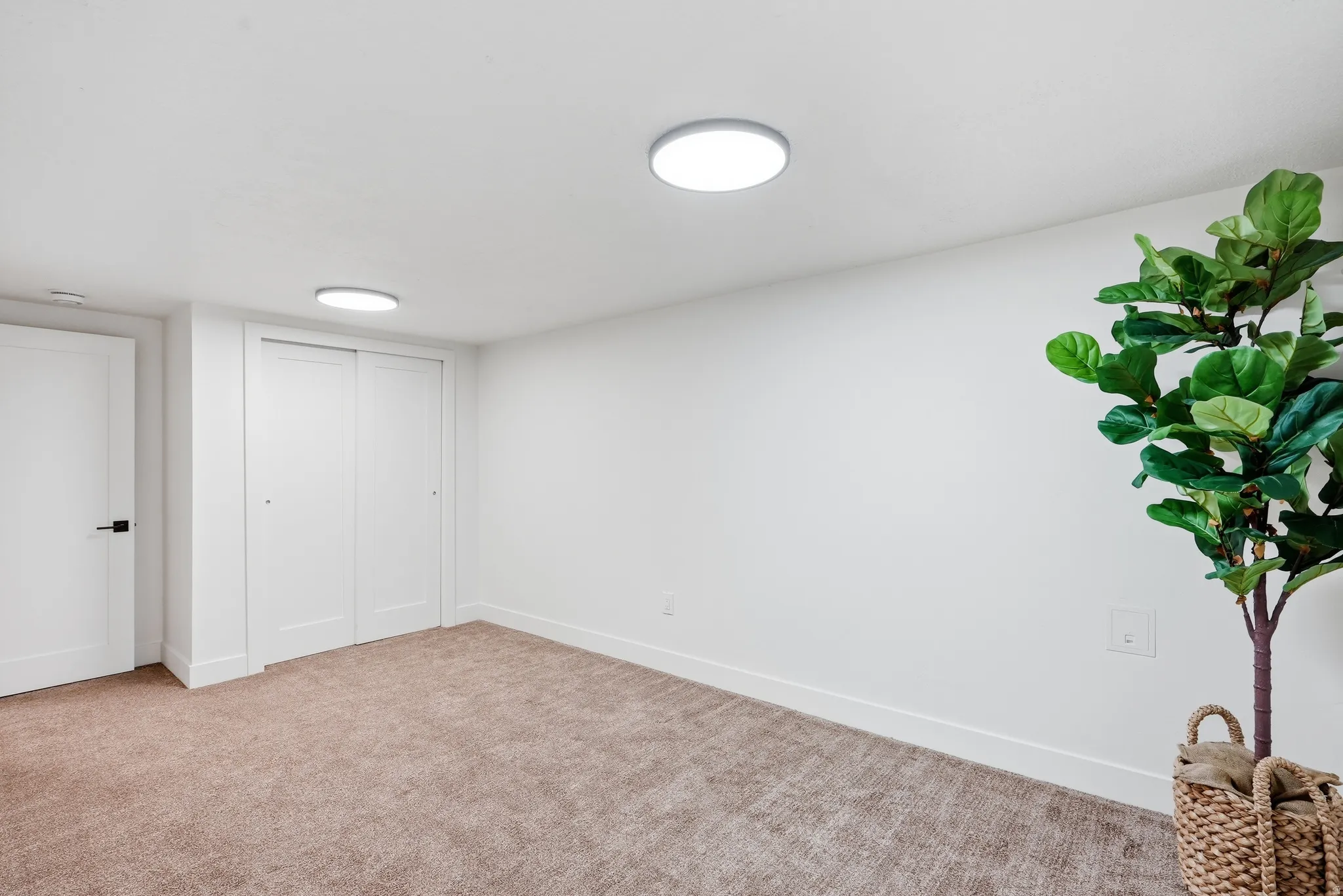 Recessed ceiling lighting, white walls, light brown carpet, white trim, and white sliding closet doors