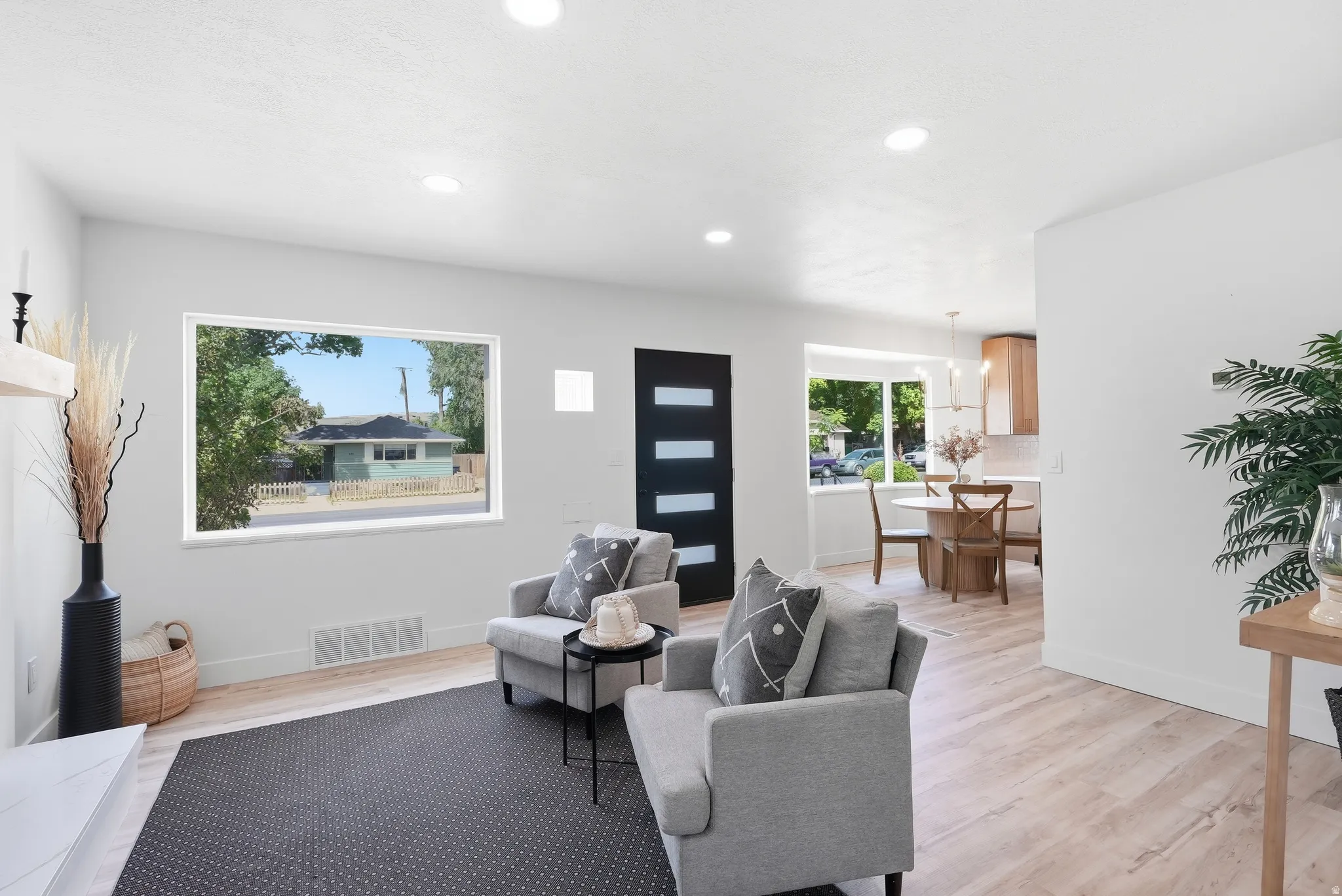 Recessed lighting, wood-finish flooring, white walls, black accent door with frosted glass panels, and a built-in fireplace mantel