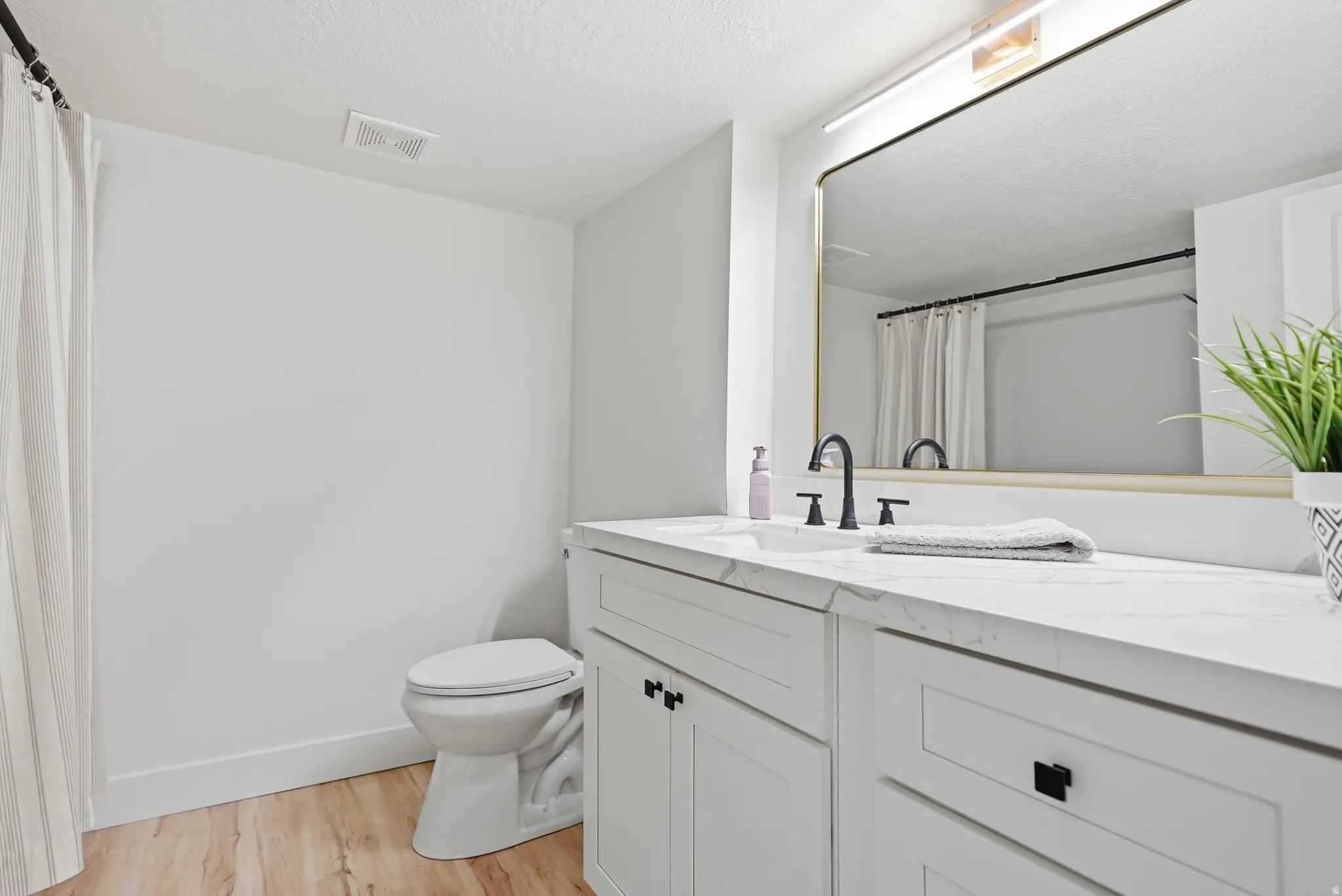 White vanity with shaker-style cabinetry, a built-in sink, and a matte black faucet