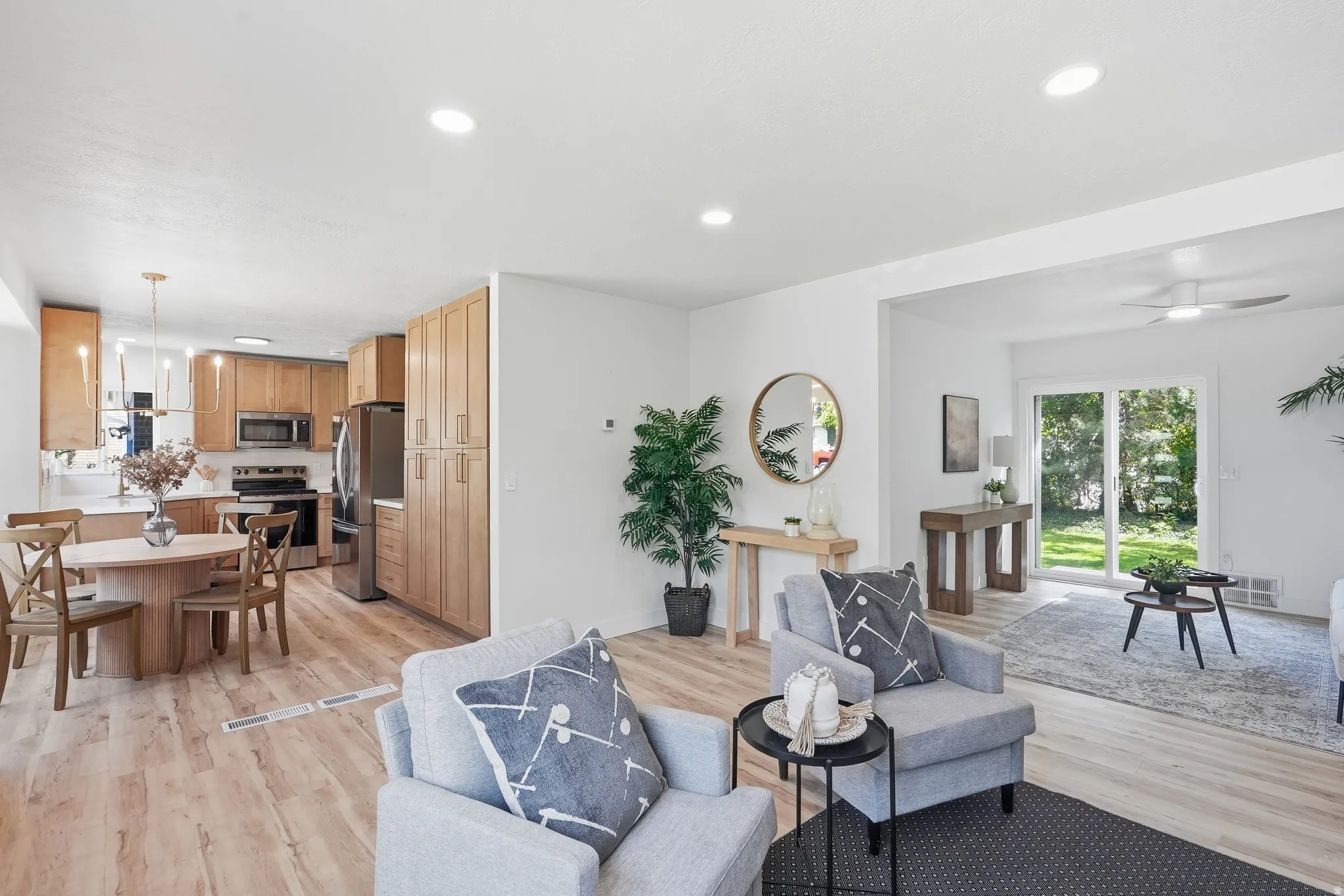 Open-concept living space with wood-finish flooring, recessed lighting, and a kitchen featuring wood cabinetry and stainless steel appliances