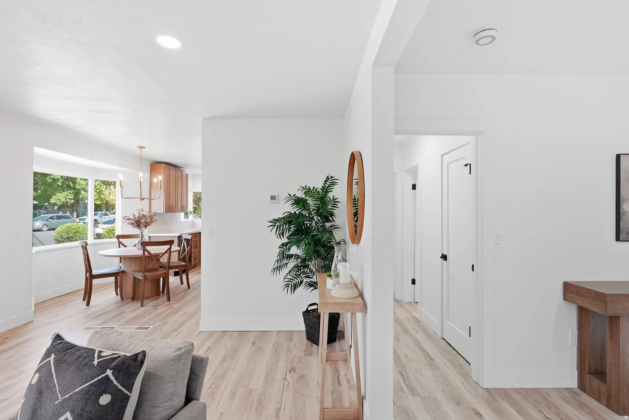 Recessed ceiling lighting, light wood-finish flooring, white painted walls, white interior doors with black hardware, and bay windows