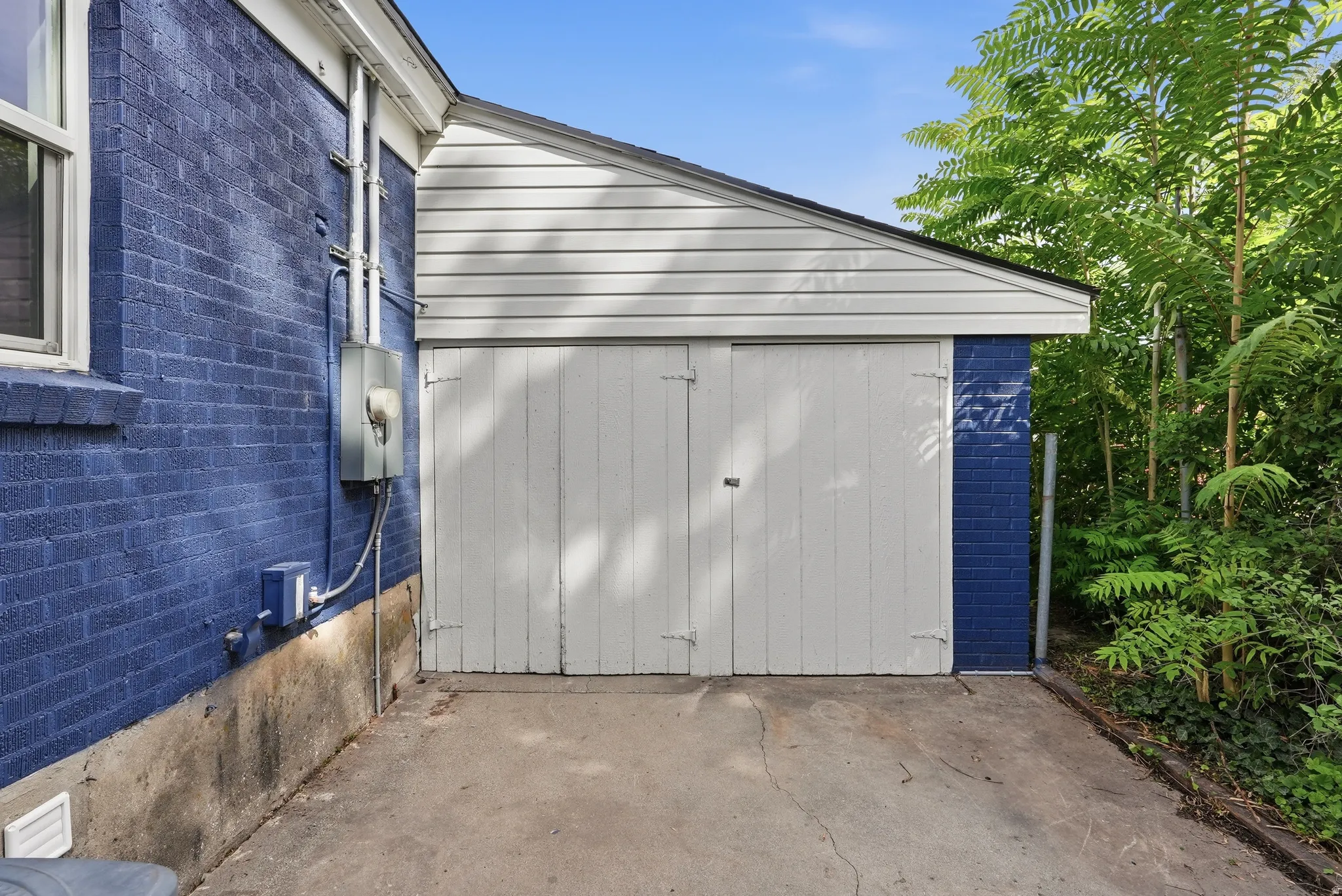 Attached garage with white panel doors and white vinyl siding