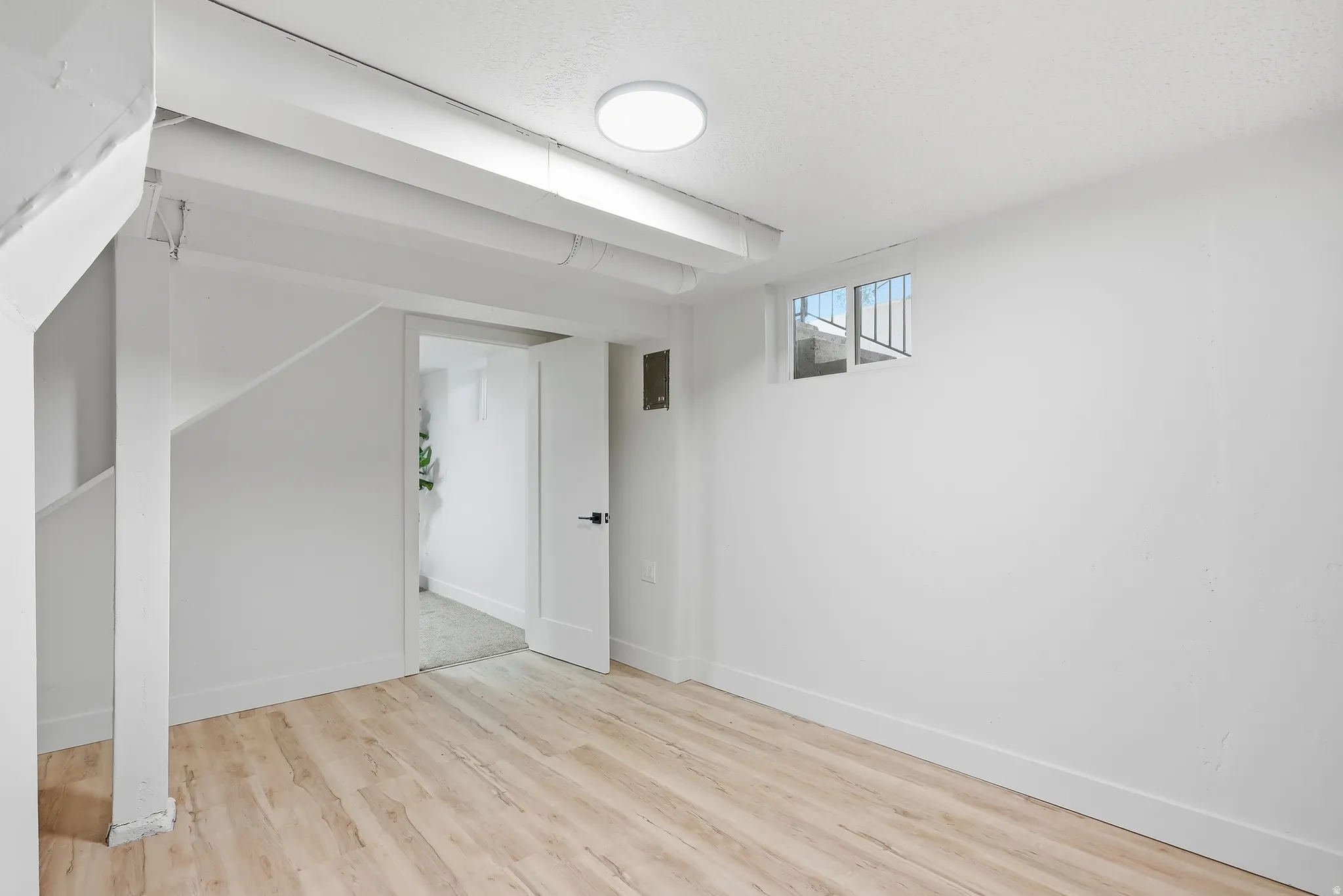 Wood-finish flooring, white walls, white trim, and a flush-mount ceiling light