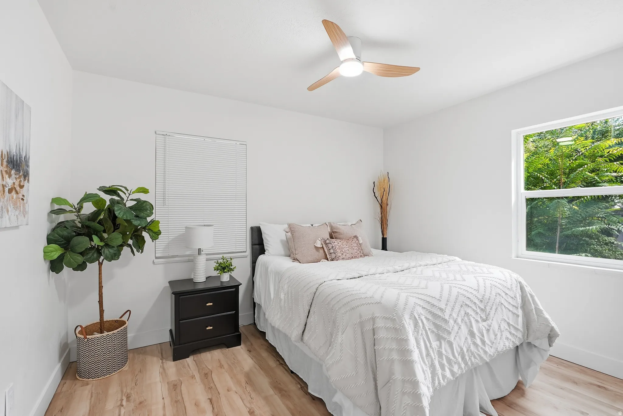 Bright interior with wood-finish flooring, a contemporary ceiling fan, and white walls