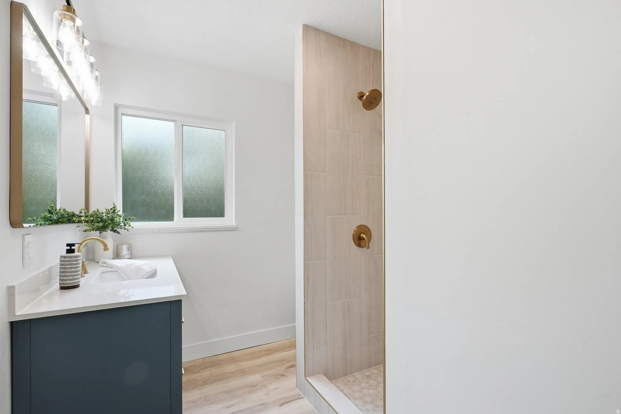 Vanity with a quartz countertop, integrated sink, and gold-finish faucet