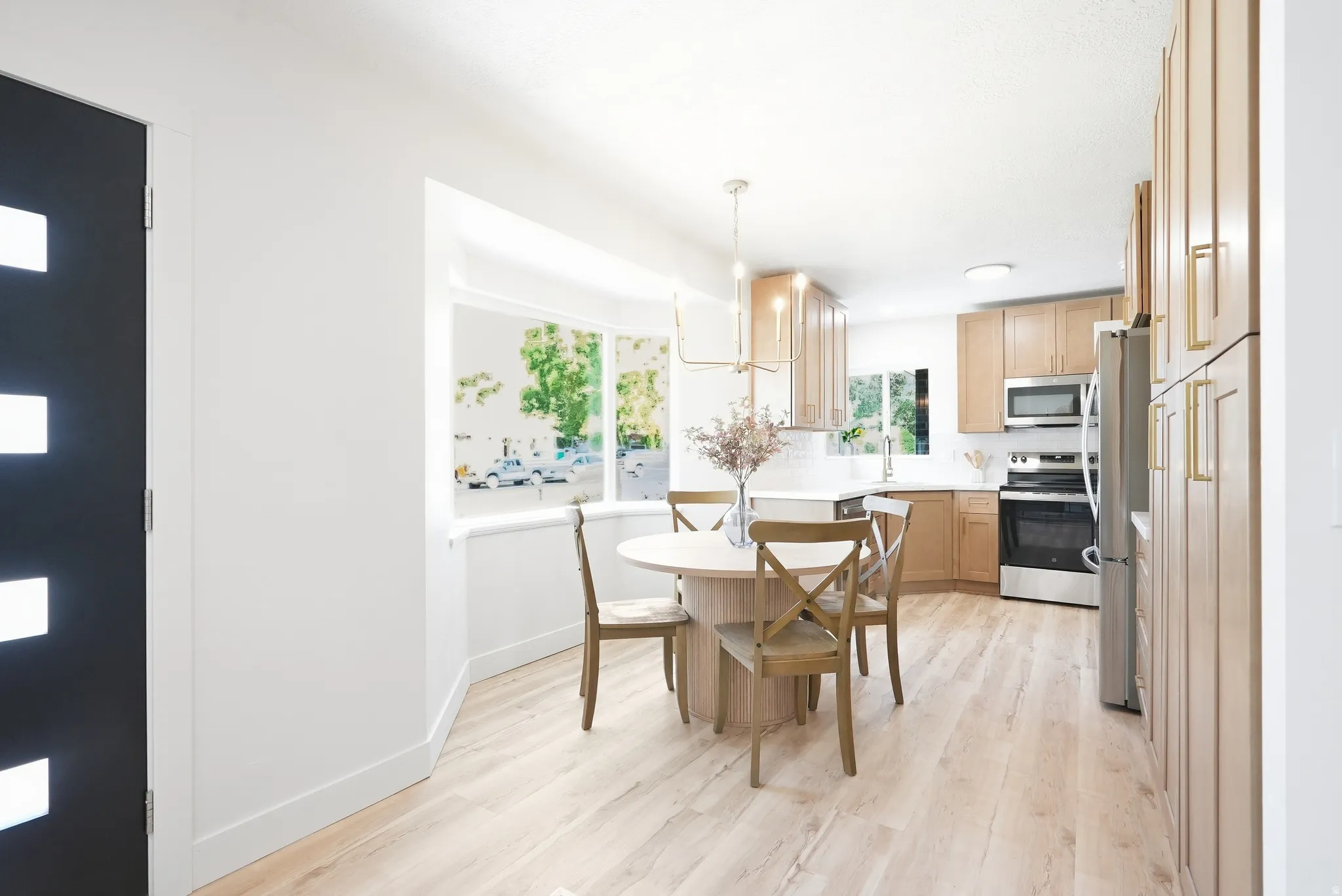 Kitchen featuring light wood-finish cabinetry, stainless steel appliances, and a white tile backsplash
