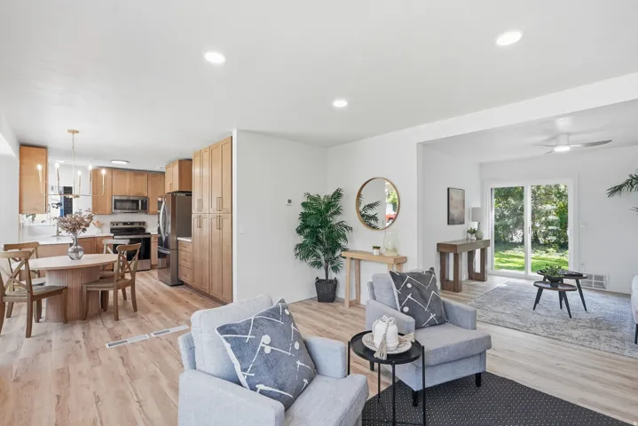 Open-concept living space with wood-finish flooring, recessed lighting, and a kitchen featuring wood cabinetry and stainless steel appliances