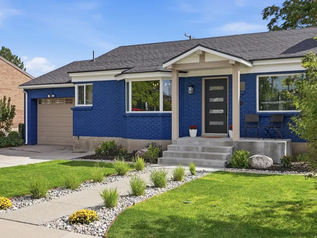 Brick exterior, covered entry, concrete walkway, attached garage, and mature landscaping