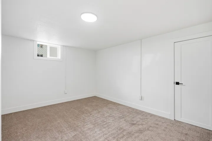 Neutral wall paint, plush carpet flooring, recessed ceiling light fixture, white trim, and a white interior door with black hardware