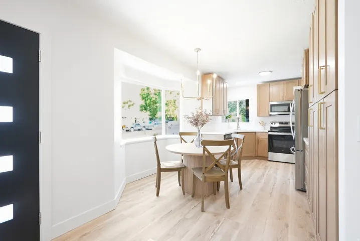 Kitchen featuring light wood-finish cabinetry, stainless steel appliances, and a white tile backsplash