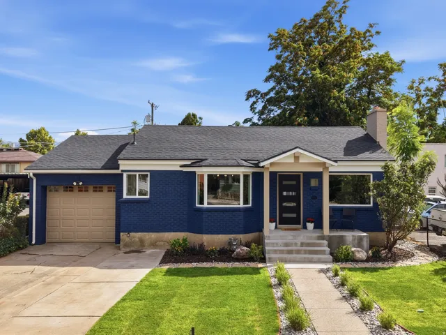Blue brick exterior with white trim, a dark shingle roof, and a single-car garage