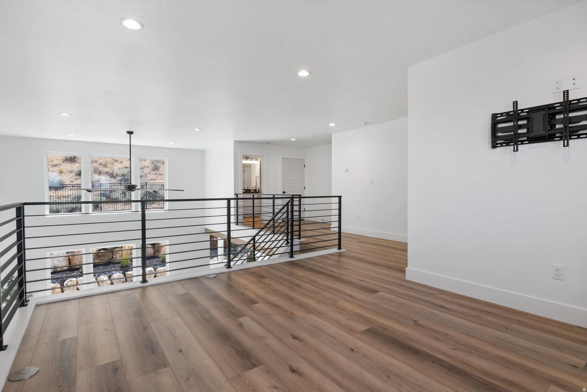 Open loft area featuring wood-finish flooring, recessed lighting, and a contemporary ceiling fan
