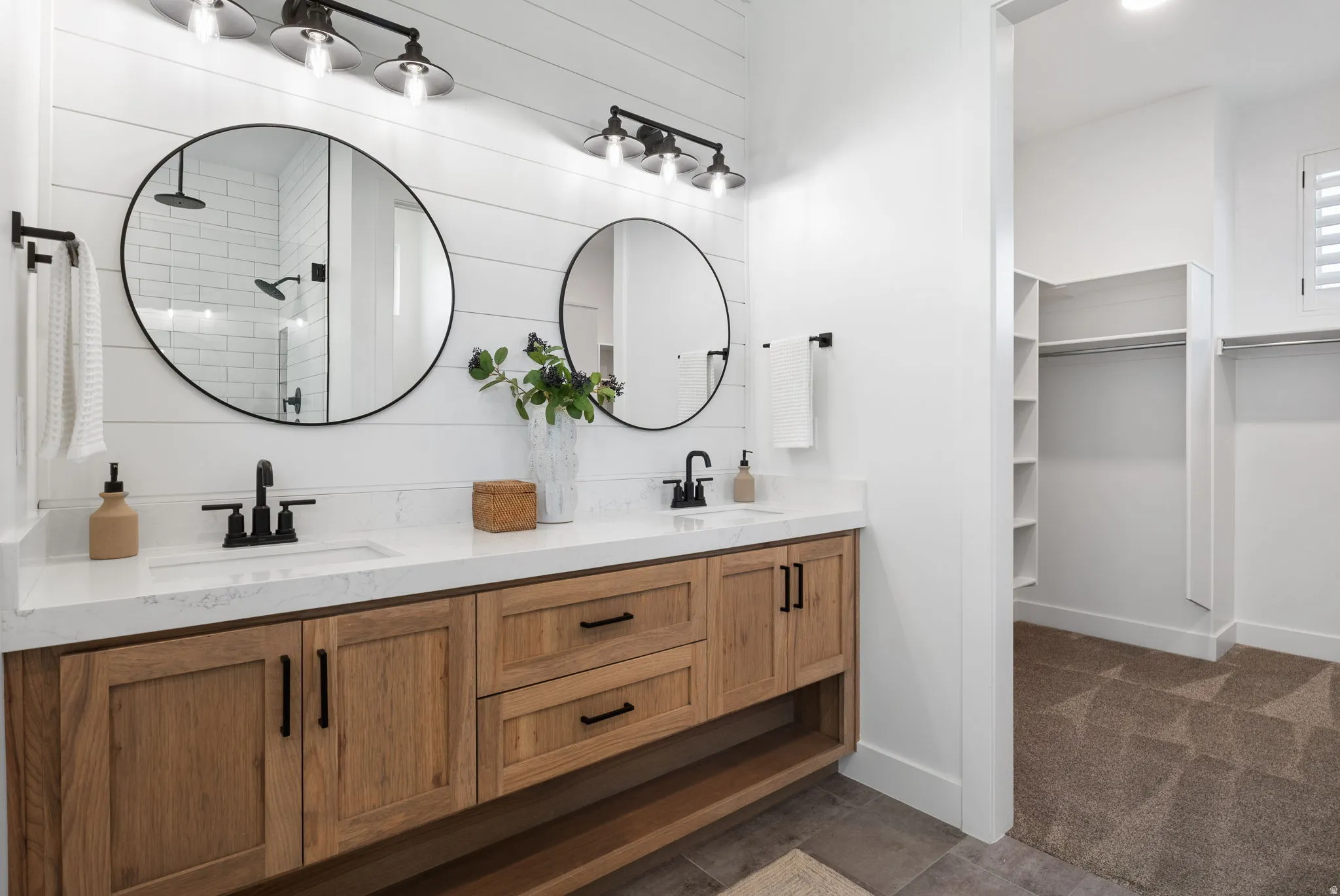 Dual vanities with white quartz countertops, wood-finish cabinetry, and matte black fixtures