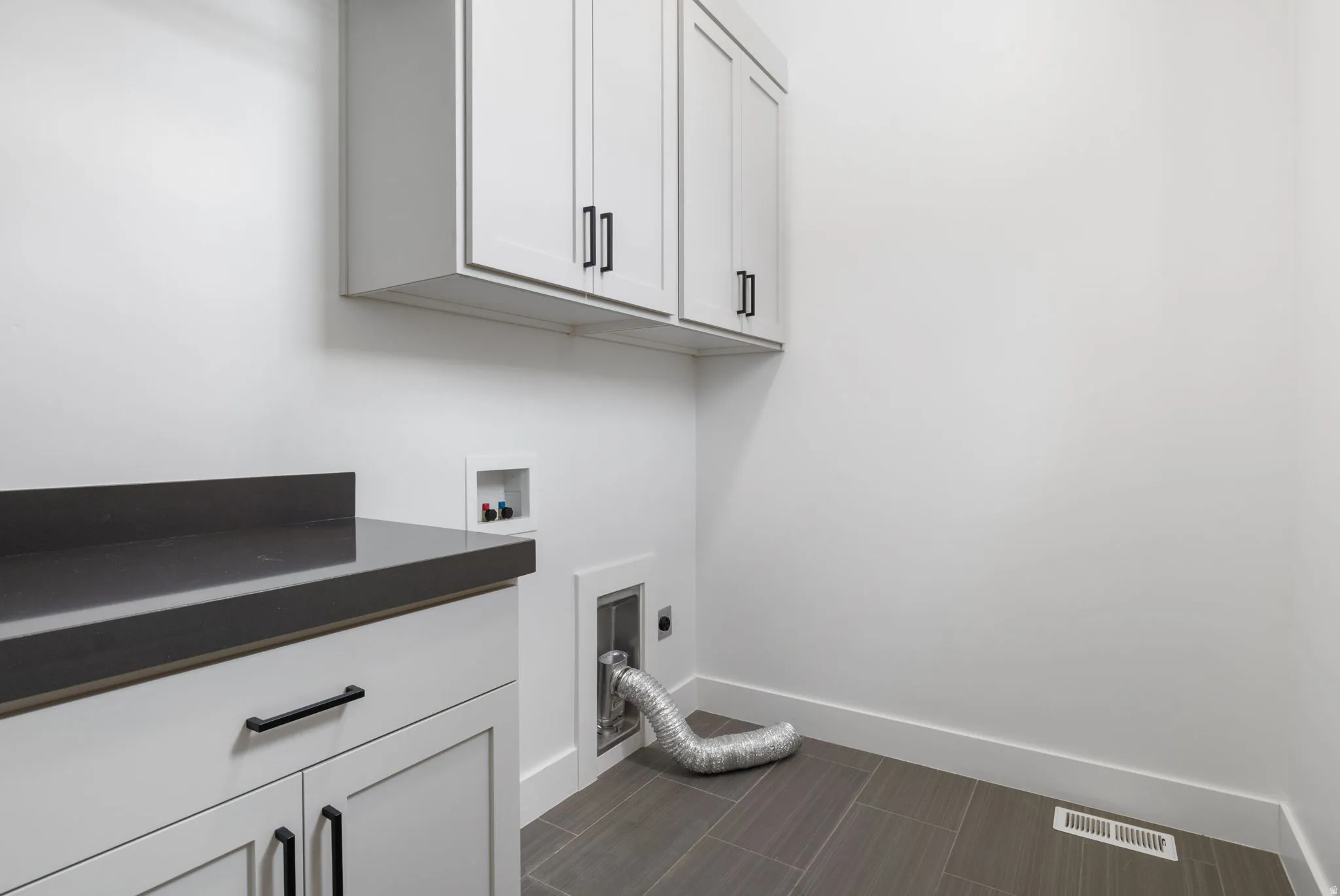 Built-in cabinetry with dark hardware, dark countertop, and tiled flooring