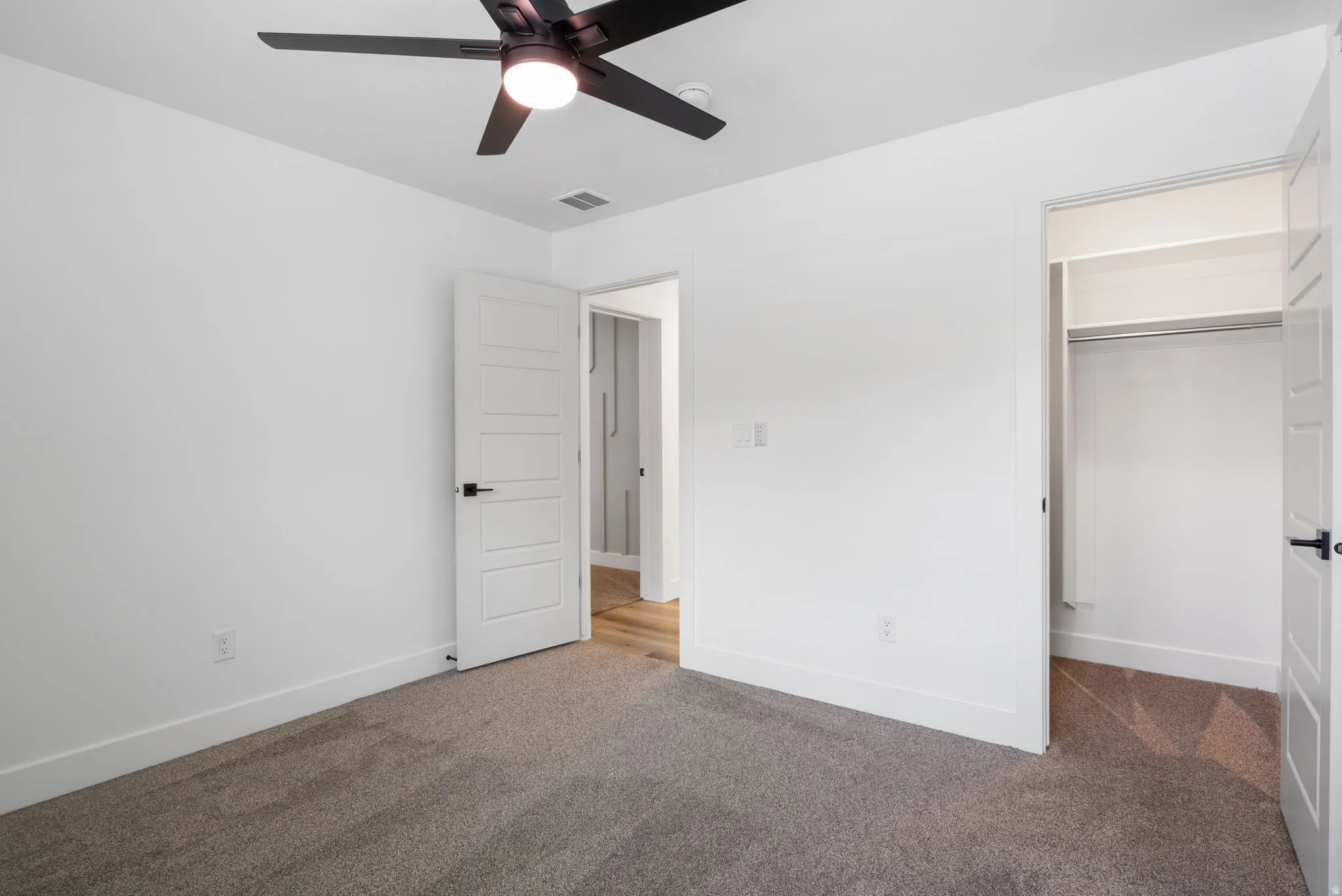 Recessed lighting, ceiling fan, white walls, carpeted flooring, and built-in closet storage