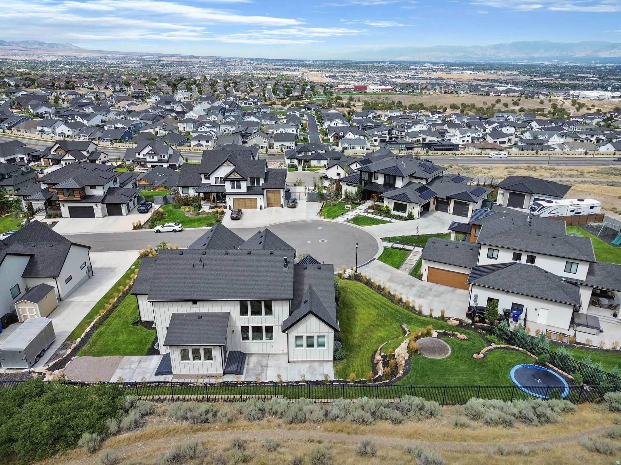 Modern residential architecture with dark roofing, a cul-de-sac street design, and landscaped yards