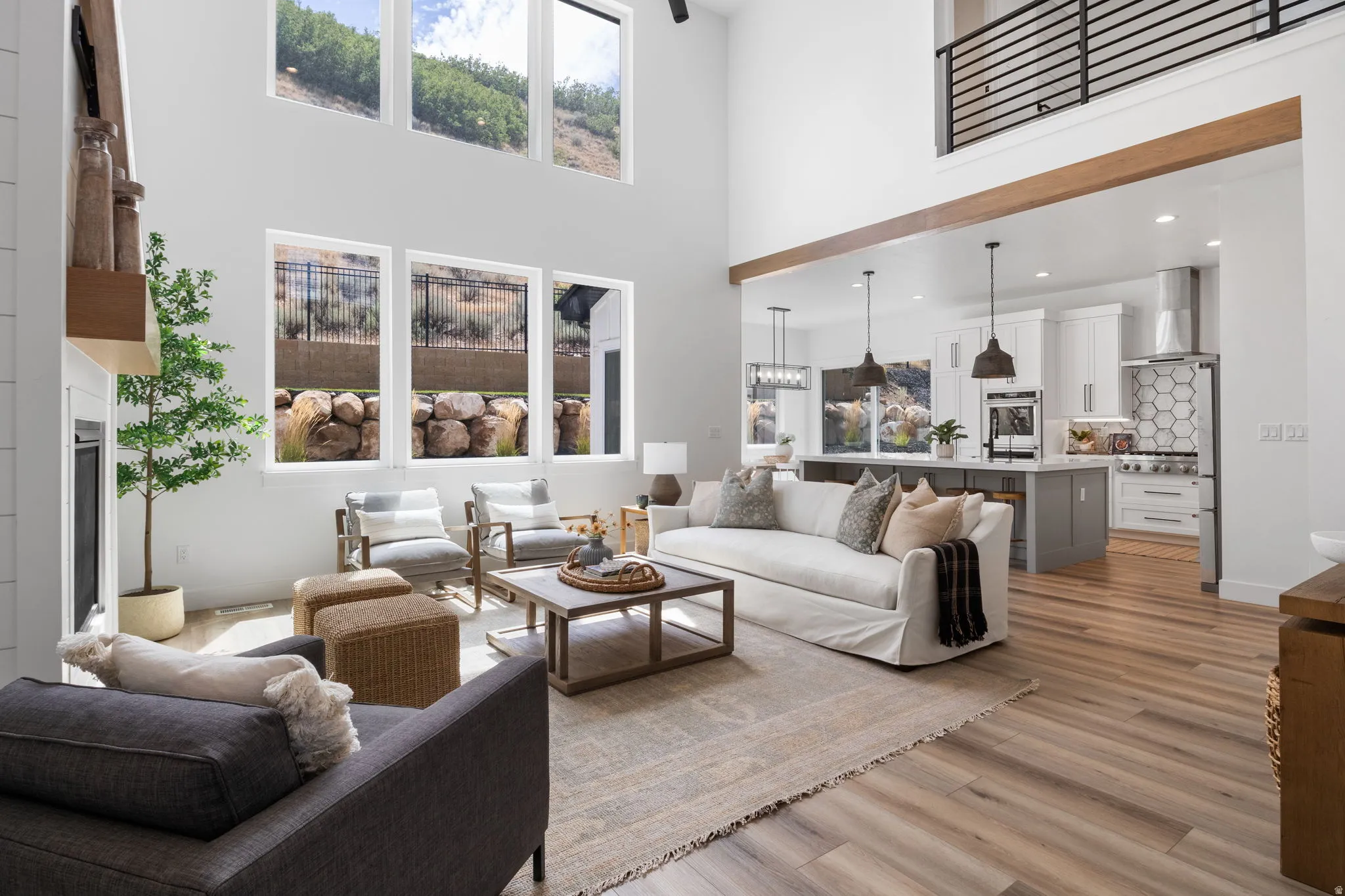 Two-story living area with high ceilings, wood-finish flooring, and multiple windows
