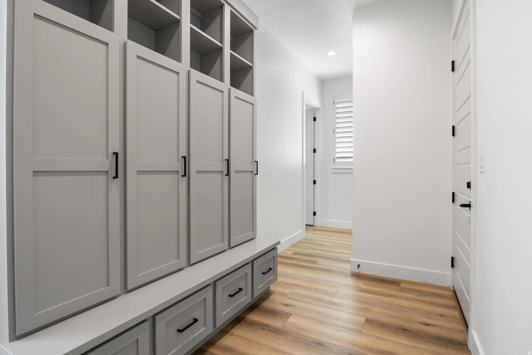 Built-in storage cabinetry with open shelving and closed compartments, integrated bench seating with drawer storage, and wood-finish flooring