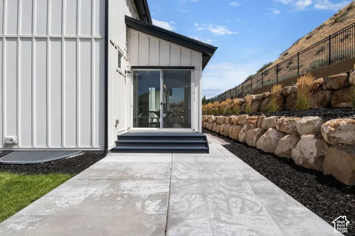Sliding glass door, raised landing, exterior steps, concrete paver pathway, and rock retaining wall