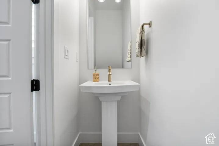 Pedestal sink with a gold-tone faucet, framed mirror, and recessed lighting
