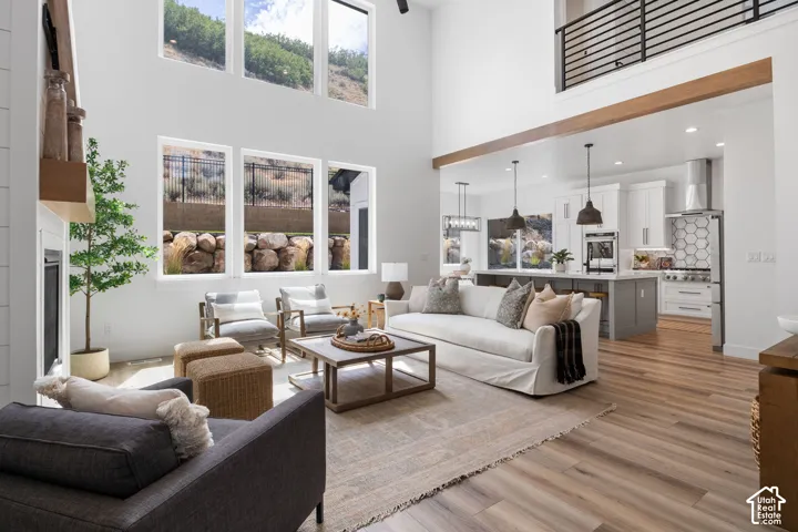 Two-story living area with high ceilings, wood-finish flooring, and multiple windows