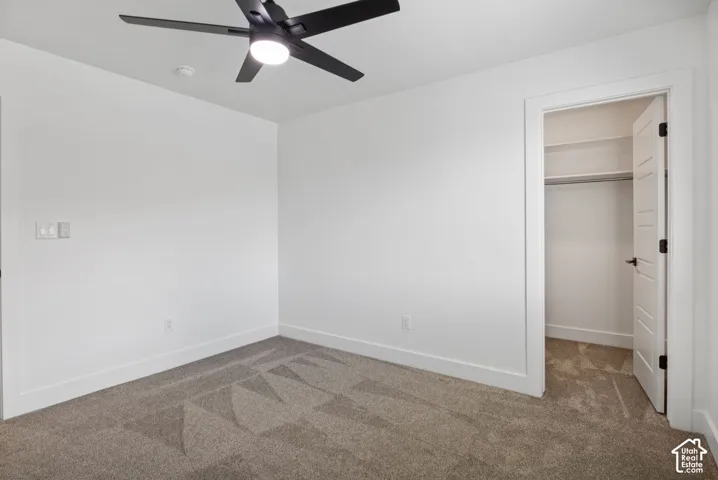 Neutral-toned carpet flooring with white walls and a contemporary black ceiling fan