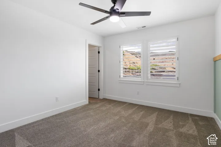 Recessed lighting, ceiling fan with integrated light, two windows with plantation shutters, mountain landscape, and carpeted flooring