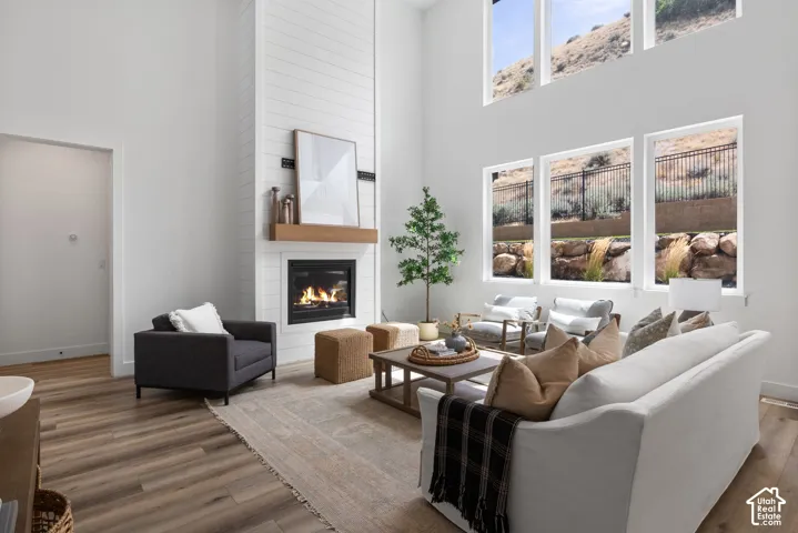 Vaulted ceilings, wood-finish flooring, a shiplap fireplace with a wood mantle, and multiple large windows