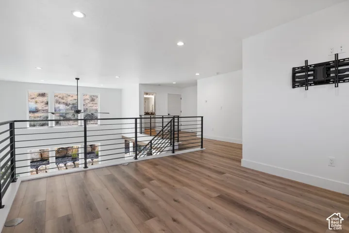 Open loft area featuring wood-finish flooring, recessed lighting, and a contemporary ceiling fan