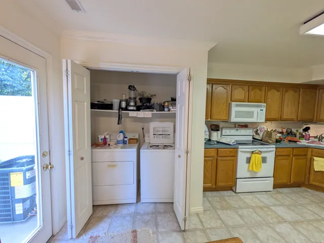 Kitchen with wood cabinetry, white appliances, and tiled flooring
