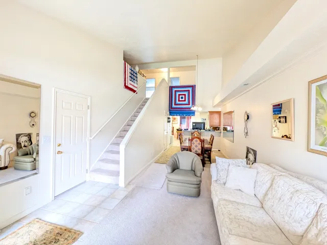 Vaulted ceilings with recessed lighting, carpeted and tiled flooring, and a staircase with an open railing