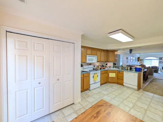 Kitchen with wood-finish cabinetry, white appliances, and a corner sink