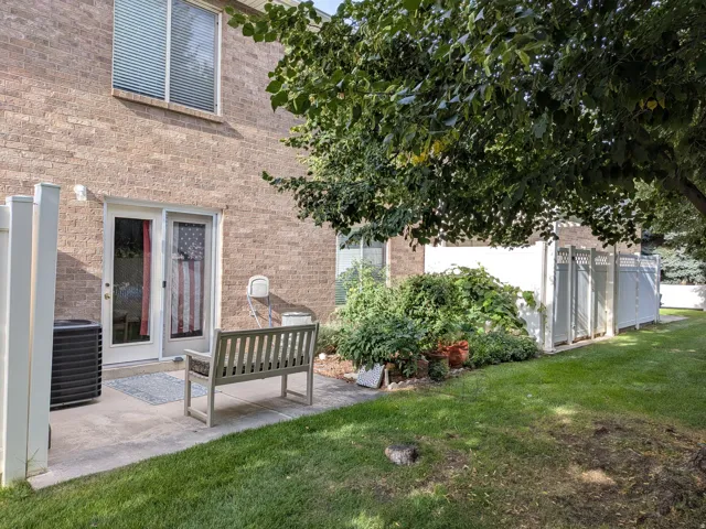Brick exterior with a ground-level patio, white sliding glass door, and a white privacy fence