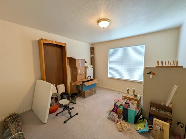 Window with blinds, wall-mounted light fixture, and textured ceiling