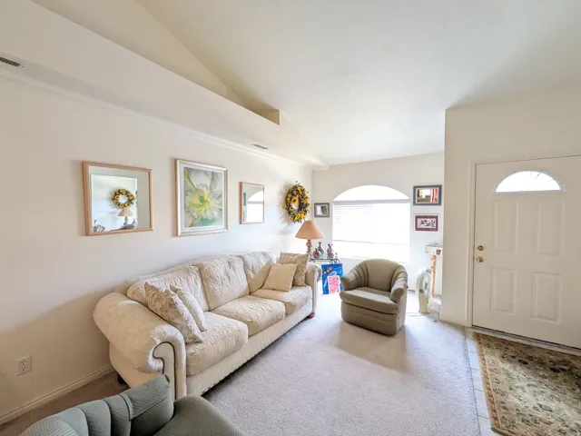 Vaulted ceiling with crown molding, arched transom window, paneled entry door with an arched glass insert, and tile flooring at entry
