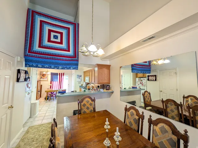 Open-concept common area featuring vaulted ceilings, a built-in wall mirror, a breakfast bar, and wood-finish cabinetry