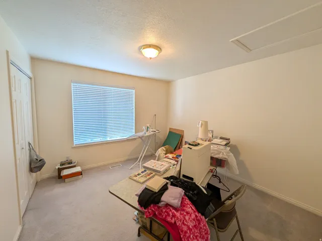 Carpeted room featuring a ceiling light fixture, window with blinds, and white walls
