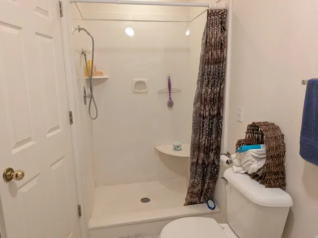 White shower enclosure with a built-in bench and recessed lighting