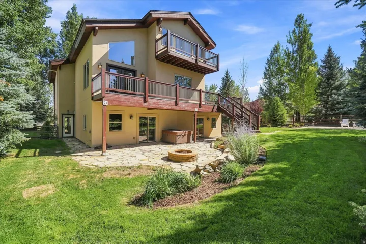 Multi-level exterior with three separate decks, ground-level stone patio, built-in fire pit, and mature perimeter trees