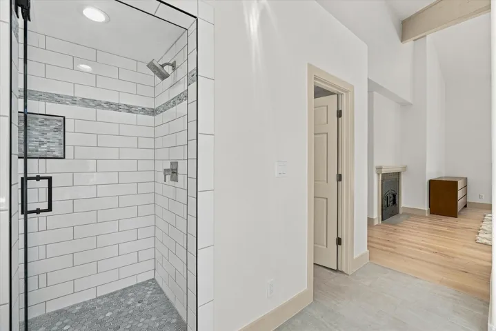 Glass-enclosed shower with subway tile surround, mosaic accent tile, built-in niche, and hexagonal floor tile