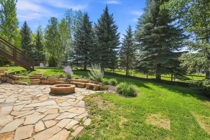 Expansive flagstone patio featuring a built-in fire pit and stone bench seating
