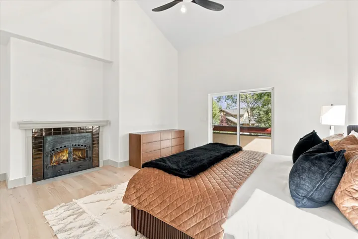 Vaulted ceilings, wood-finish flooring, and a fireplace with a decorative tile surround