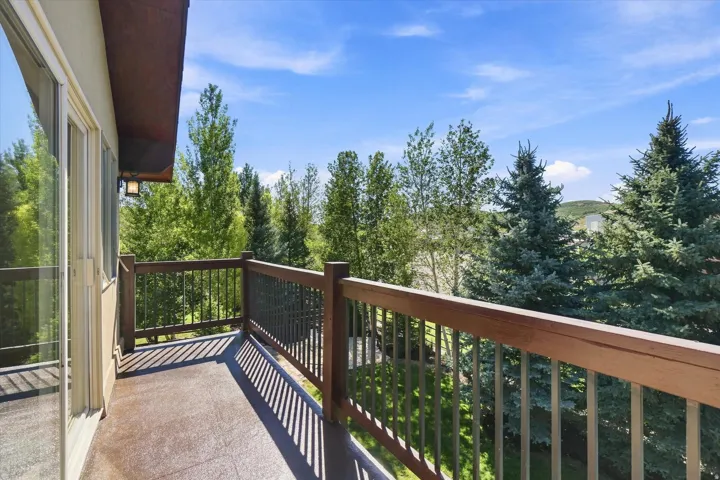 Spacious outdoor balcony with a wood railing, metal balusters, and a textured deck surface