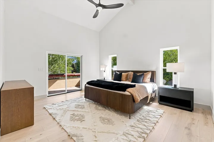Vaulted ceilings with a ceiling fan, light wood-finish flooring, and white walls