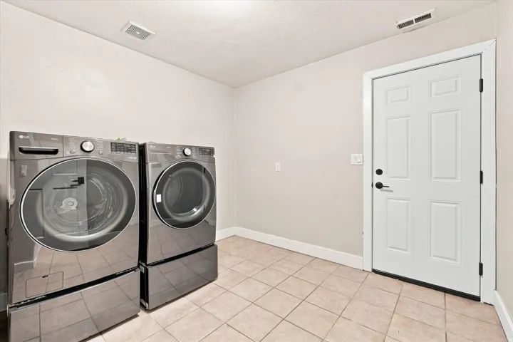 Laundry area with tile flooring and a paneled door