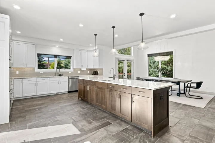 Gourmet kitchen with white shaker cabinetry, stainless steel appliances, a tile backsplash, and a spacious center island with seating