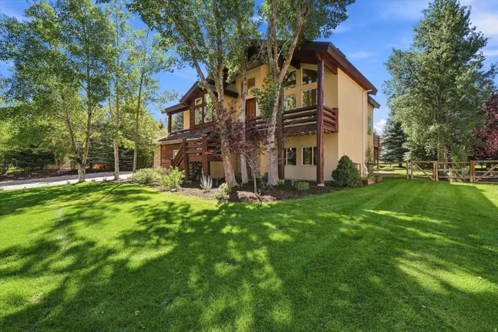 Multi-level residence featuring a stucco exterior, wood-finish balconies, and multiple large windows
