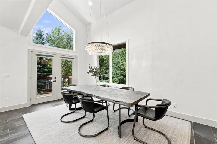 Vaulted ceilings with exposed beams, floor-to-ceiling windows, and French patio doors