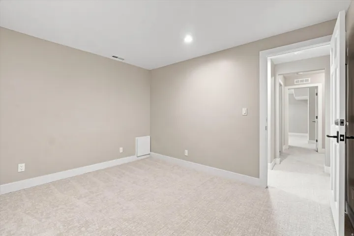 Wall-to-wall carpeting with recessed lighting and a solid core interior door